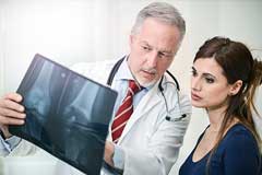 Arzt erklärt seiner Patientin die Röntgenaufnahme des Knies