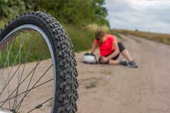 Gestürzte Radfahrerin hält sich verletztes Knie