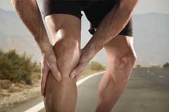 Junger, trainierter Läufer hält sich schmerzendes Knie