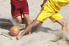 Nahaufnahme von zwei Strandfußballern im Zweikampf um den Ball