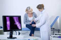 Ärztin untersucht das Knie einer Patientin